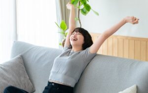 ソファで腕を伸ばしくつろぐ女性|開運御片付け終わって笑顔のイメージ
