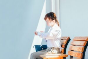 駅で腕時計を見る働く女性